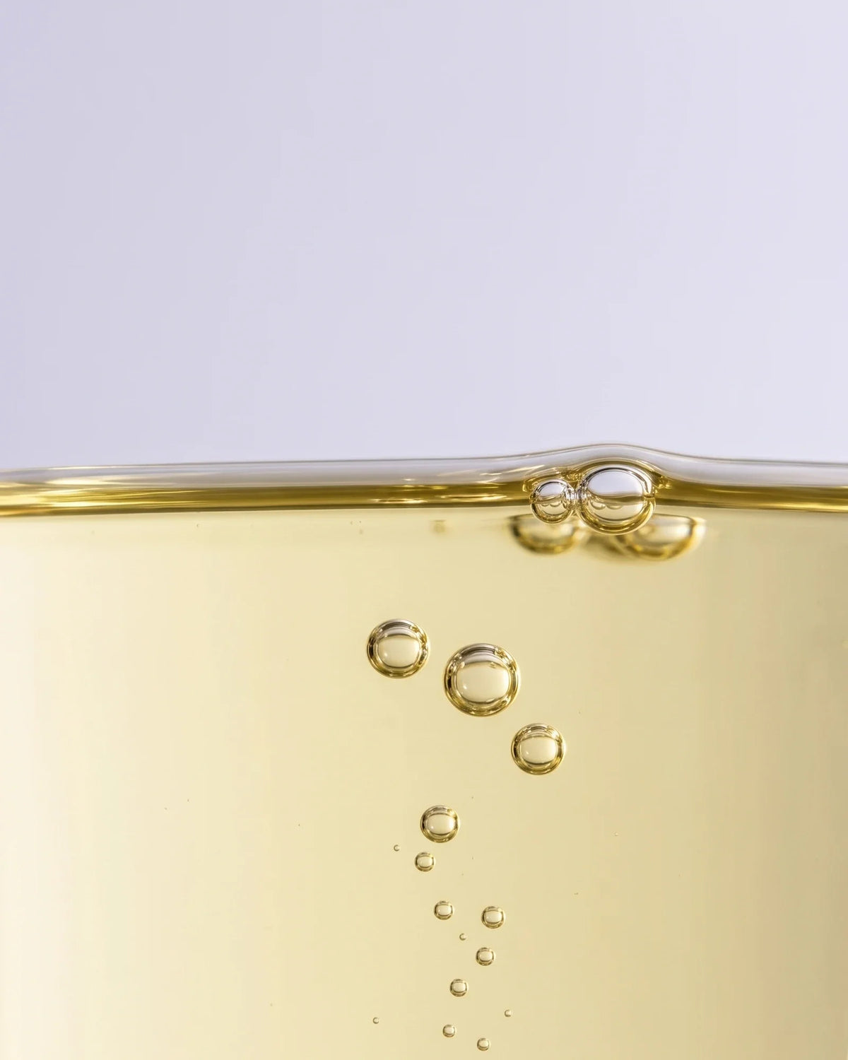 Textura do sérum-óleo Calm 49% de marula: óleo de marula dourado-claro com bolhas subindo suavemente