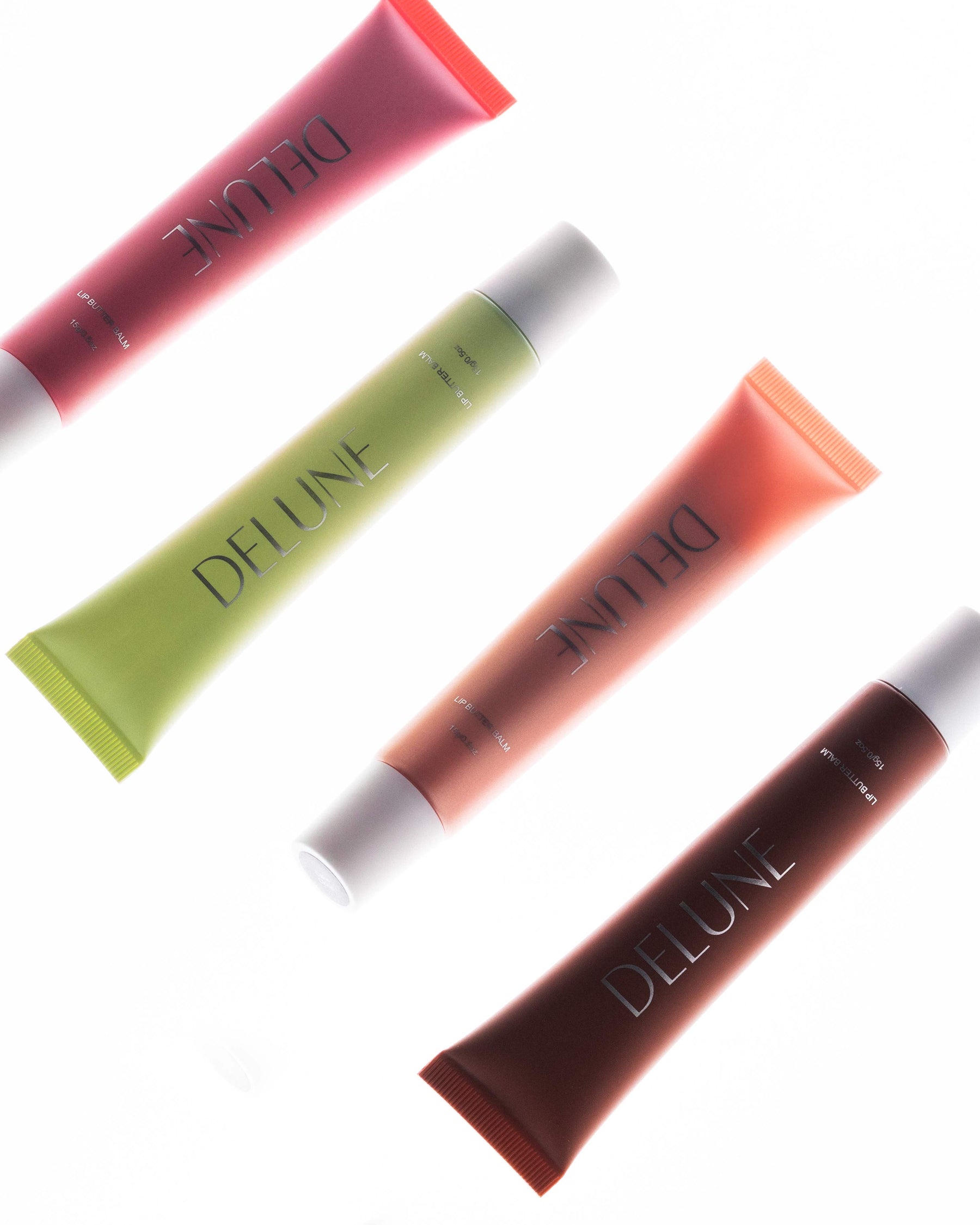Quatro tonalidades do Lip Butter Balm da Delune com amostras de brilho