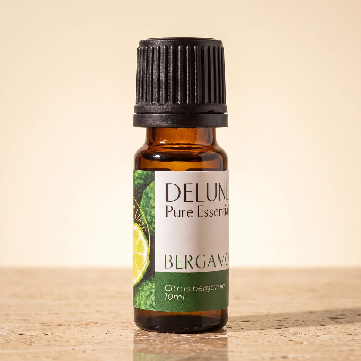 Óleo essencial puro de bergamota Delune, frasco âmbar de 10 ml sobre travertino quente
