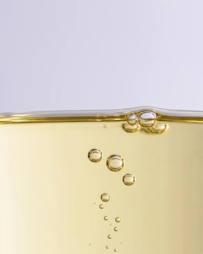 Textura do sérum-óleo Calm 49% de marula: óleo de marula dourado-claro com bolhas subindo suavemente