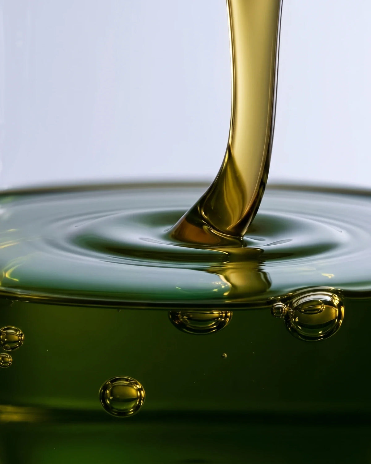 Textura do sérum-óleo Clear 49% de tamanu: óleo verde-dourado de tamanu escorrendo em ondas suaves