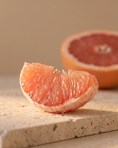 Um gomo reluzente de toranja-rosa à contraluz do sol quente — o aroma agridoce e suculento do Óleo essencial puro de toranja-rosa Delune
