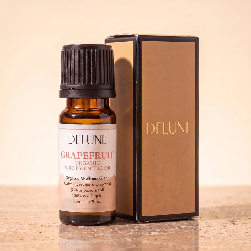 Óleo essencial orgânico de toranja Delune, frasco âmbar de 10 ml com a caixa de presente dourada Delune sobre travertino quente
