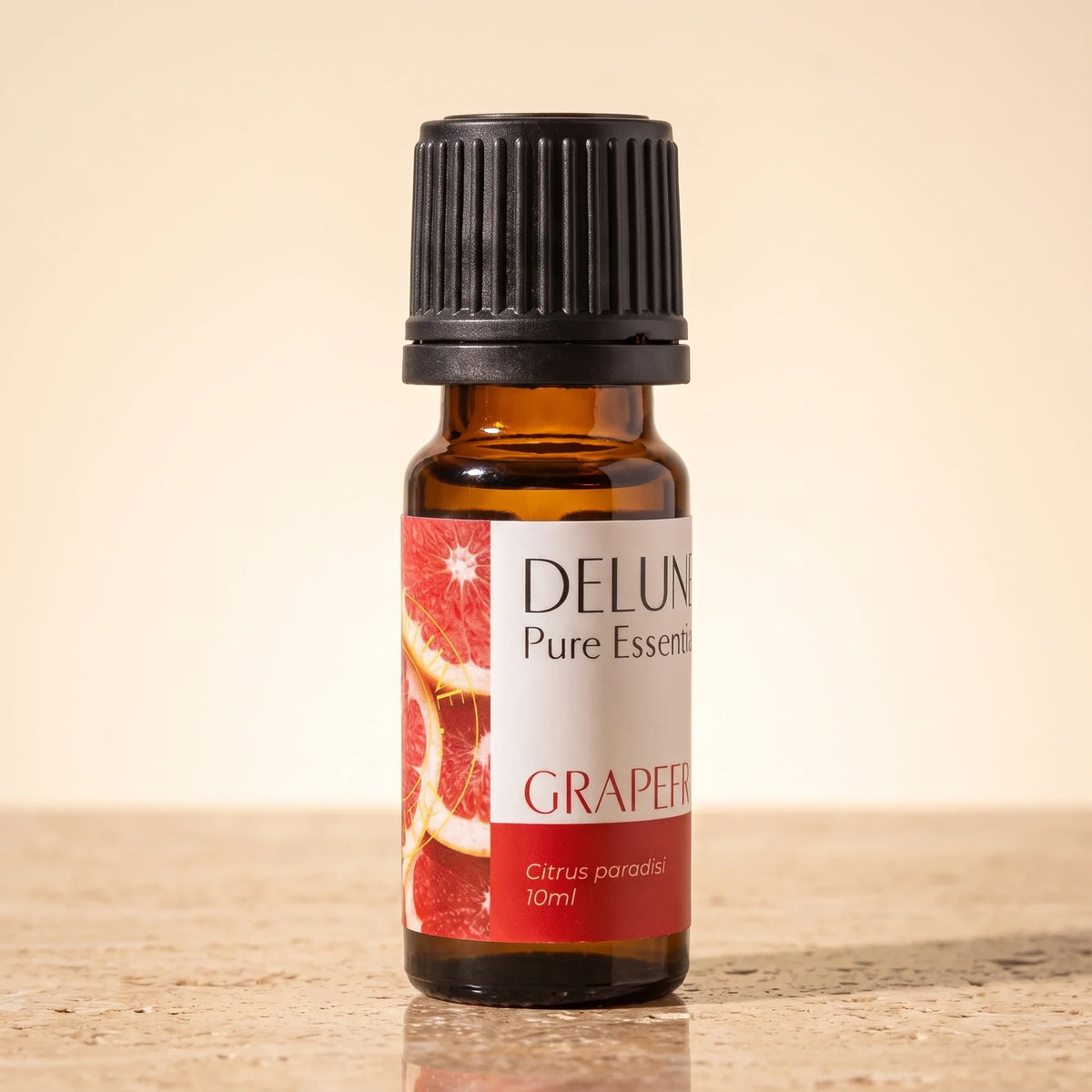Óleo essencial puro de toranja-rosa Delune, frasco âmbar de 10 ml sobre travertino quente