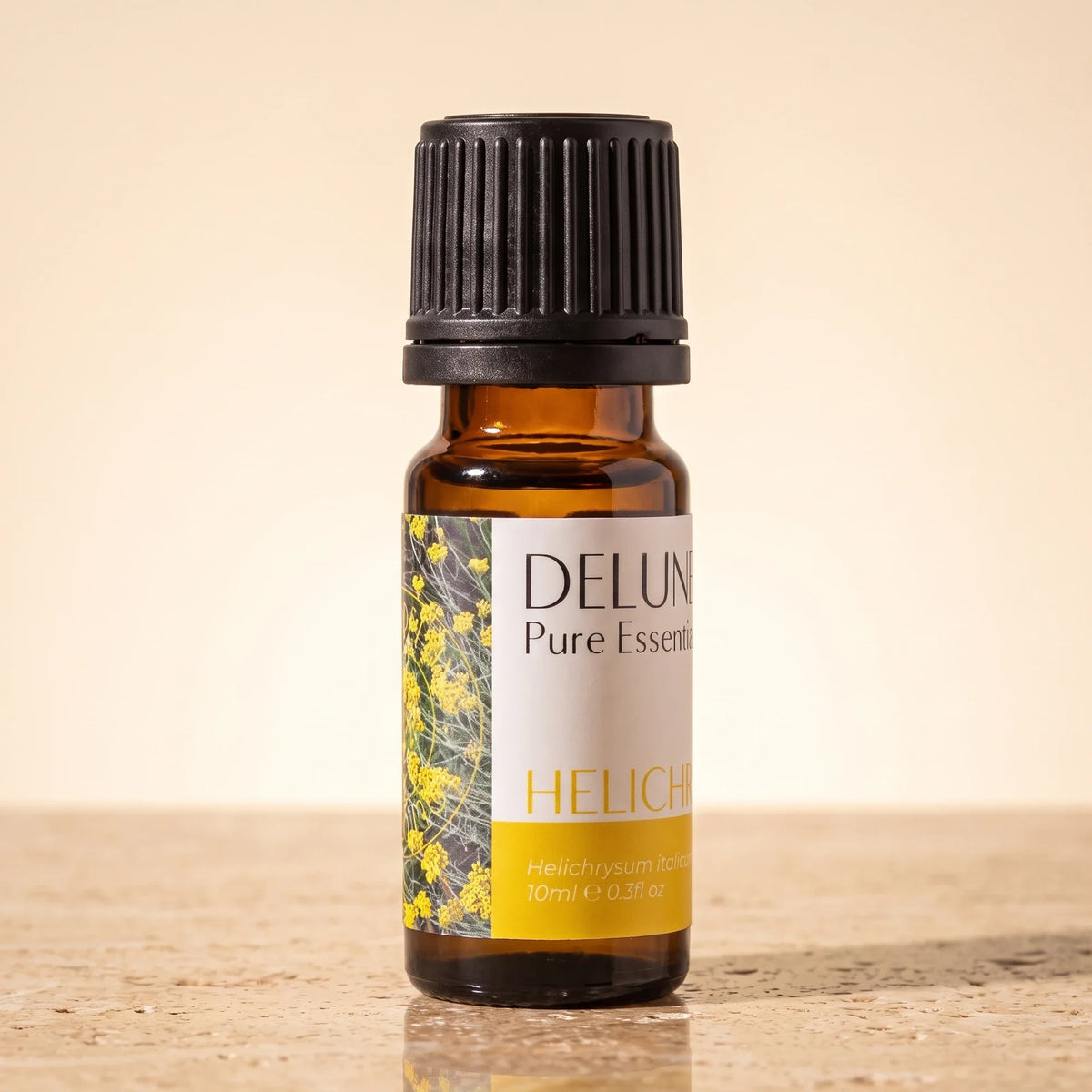 Óleo essencial puro de helicriso (imortela) Delune, frasco âmbar de 10 ml sobre travertino quente