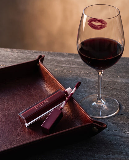 Batom LuxMatte Delune no tom Cabernet Kiss com uma taça de cabernet