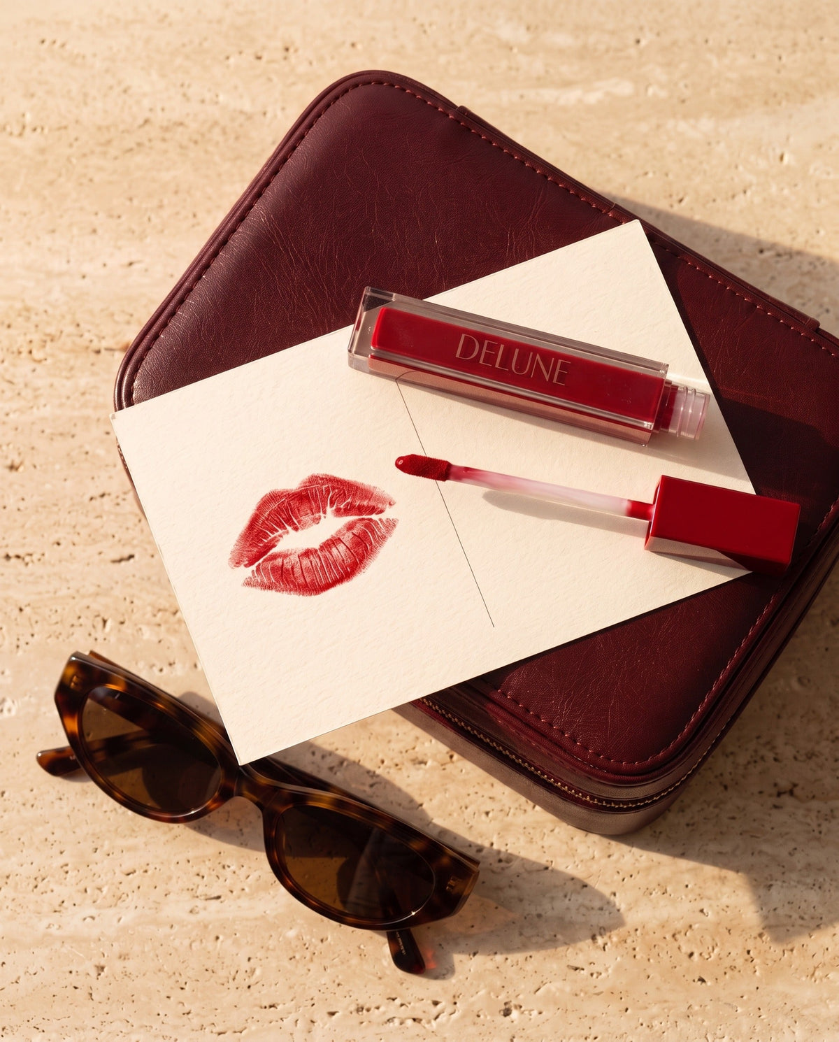 Batom LuxMatte Delune no tom Jet-Set Red com um beijo vermelho em um cartão-postal