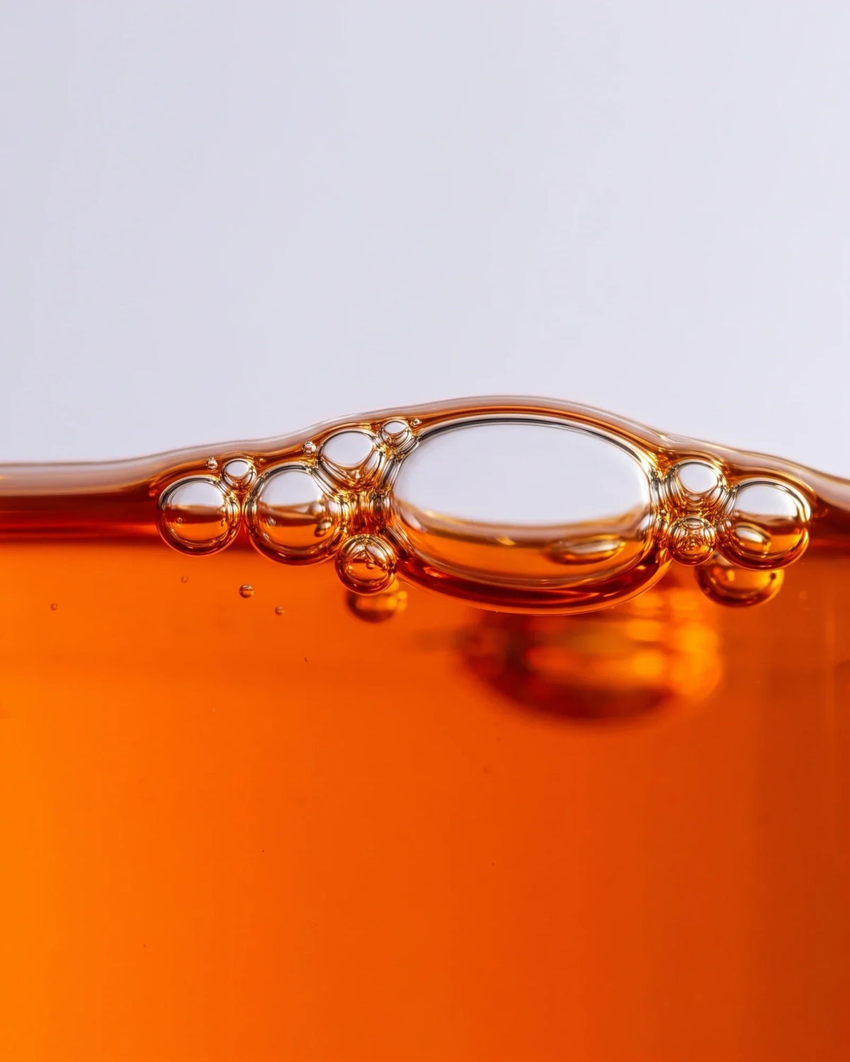 Textura do sérum-óleo Revive 49% de espinheiro-marítimo: macro do óleo laranja vivo com bolhas na superfície