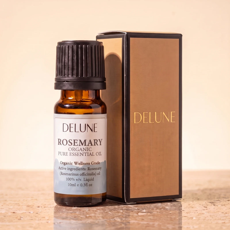 Óleo essencial orgânico de alecrim Delune, frasco âmbar de 10 ml com a caixa de presente dourada Delune sobre travertino quente