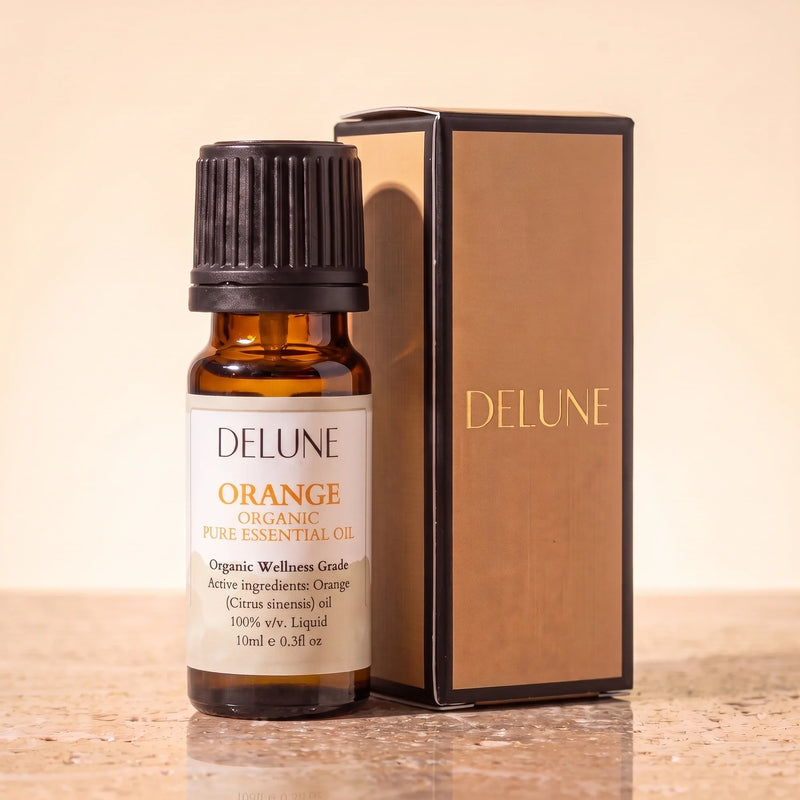 Óleo essencial orgânico de laranja-doce Delune, frasco âmbar de 10 ml com a caixa de presente dourada Delune sobre travertino quente