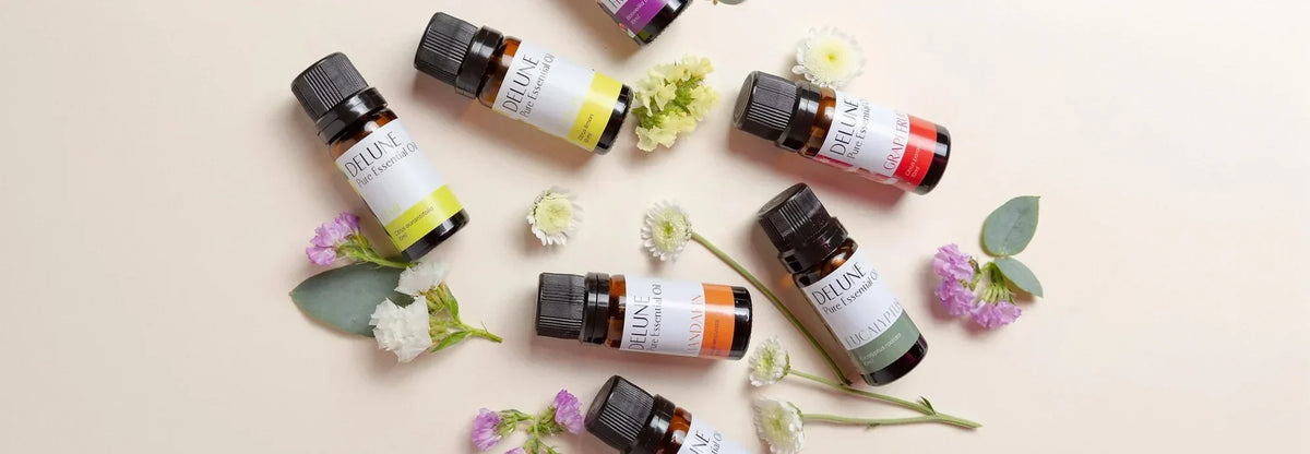 Frascos de óleos essenciais Delune dispostos com flores frescas e eucalipto